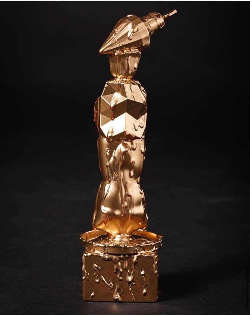 Sculpture dorée à chapeau conique et corps facetté, de face